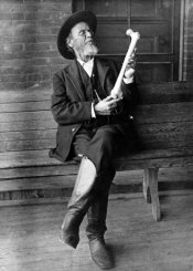 Der Begründer der Osteopathie Andrew Taylor Still beim Betrachten eines Oberschenkelknochens. Er trägt Hut und sitzt auf 1 Bank Der Begründer der Osteopathie Andrew Taylor Still beim Betrachten eines Oberschenkelknochens. Er trägt Hut und sitzt auf 1 Bank